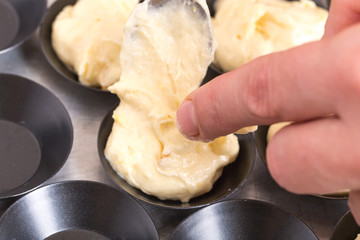 Taking muffin dough to baking pan.