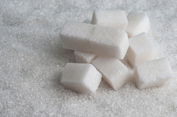 cubes of sugar on white granulated sugar background