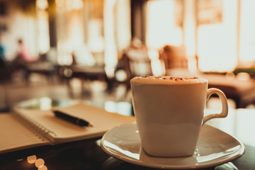 Capuccino coffee and notebook on table