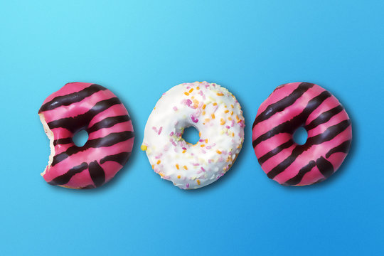 Set of donuts with pink glaze and various toppings on blue background. Poster.