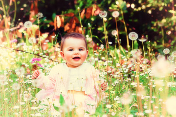 Beautiful baby girl among spring flowers