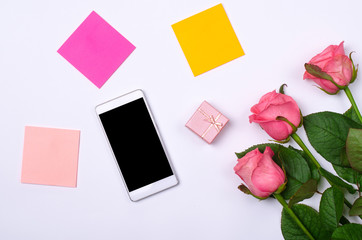 Smartphone and pink roses on a white background.