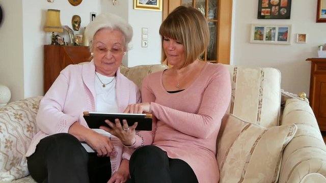 Seniorin mit Tochter/Enkelin/Betreuerin und Tablet Computer