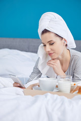 Portrait of a happy smiling european woman eating a healthy breakfast of fruit and yoghurt in bed.