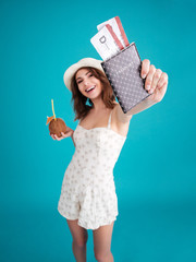 Girl traveller in summer clothes showing passport with tickets