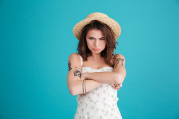 Portrait of grumpy moody girl in straw hat standing