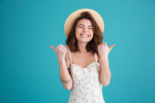 Happy young girl wearing straw hat and showing thumbs up
