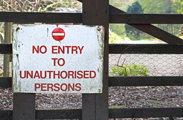 Wooden sign on a gate saying 'no entry to unauthorise persons' , with bokeh view through to land...