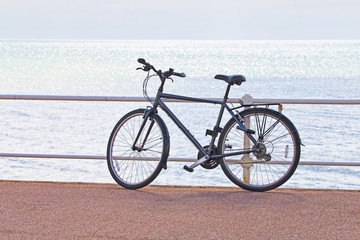 Fototapeta na wymiar A man's bicycle propped against railings on the seafront with bright sea in the background.