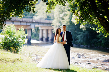 Lovely wedding couple at amazing landscapes stay against mountain river.