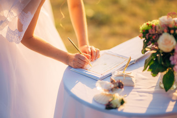 Newlyweds put their signatures in the act of registering a marriage at a wedding ceremony in...