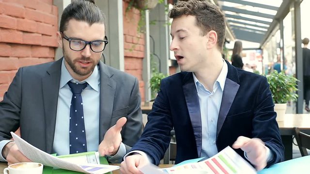 Businessmen having an argument with each other while working on papers, steadycam shot
