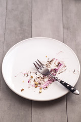 White empty plate with piece of cake leftovers from above on gray background. Copyspace for text