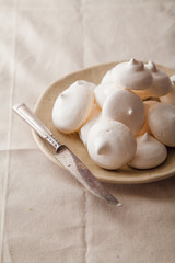 Homemade meringues on ceramic plate and linen fabric