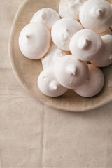 Homemade meringues on ceramic plate and linen fabric