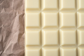 Close-up of white chocolate bar over paper
