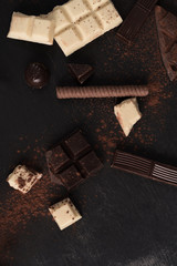 Chocolate bar pieces and candies over wooden surface