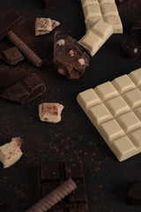 Chocolate bar pieces and candies over wooden surface