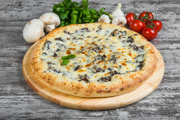 Pizza with chicken and mushrooms with rosemary and spices on a light wooden background. Italian pizza on a background of green basil and fresh vegetables