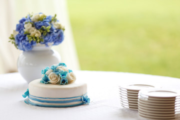 Fototapeta na wymiar Wedding decoration with a cake and a vase with blue and white flowers
