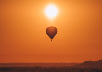 Silhouette of hot air balloon over Bagan in Myanmar, tourists watching sunrise over ancient city