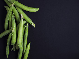 Green peas in pods isolated on black background