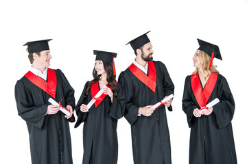 Group of young men and women in graduation gowns and mortarboards holding diplomas