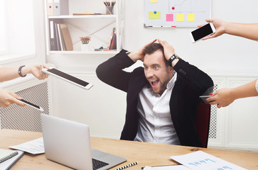 Young stressed overworked businessman in modern office