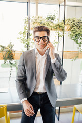 Handsome young freelance business man speak on phone in modern office