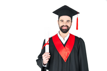Happy young man in graduation hat holding diploma and looking at camera