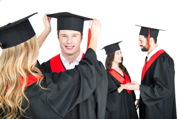 girl fixing student's graduation cap isolated on white