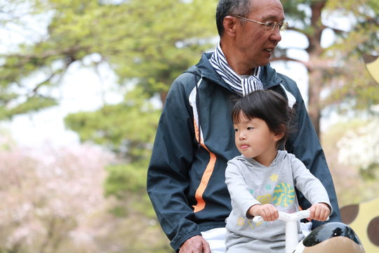 おじいちゃんと遊具に乗る子供