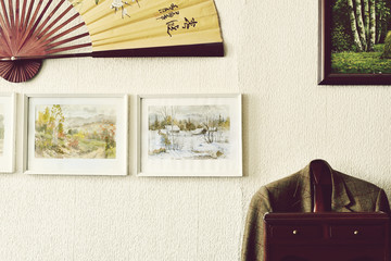 Posters in white frames, Japanese paper fan on a white wall, men's jacket on a standing hanger