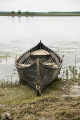 Old boat on the shore of danube river chained to a pole