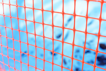 Plastic safety net for construction site. Construction mesh on winter snow background