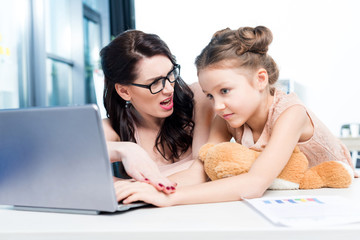 young businesswoman working with little adorable daughter in office