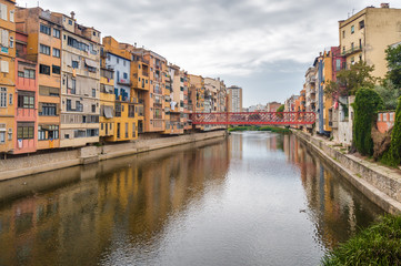 Naklejka na ściany i meble Cloudy view of riverside and bridge over river Onyar, Girona, Catalonia, Spain.