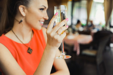 close-up portrait of a beautiful young elegant sexy blonde woman in the cafe with a glass of champagne,White wine smiling and drink posing, with a ring on her finger, she is engaged