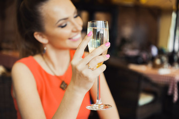 close-up portrait of a beautiful young elegant sexy blonde woman in the cafe with a glass of champagne,White wine smiling and drink posing, with a ring on her finger, she is engaged