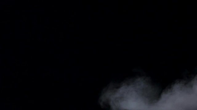 White haze swirls on isolated black studio background, slow motion