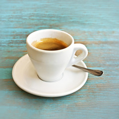 Photo of white cup of coffee on teal blue table