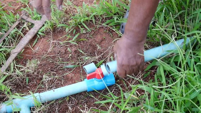 Thai fat man older work repairing and connect pipe in garden at agricultural countryside farm in Phatthalung province of southern Thailand.