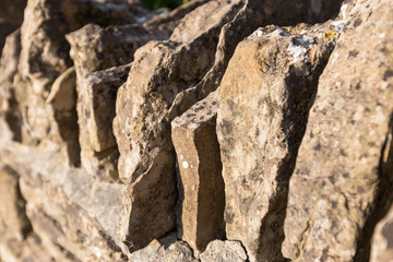 close up of stacked and lined up or large old stones to form a wall