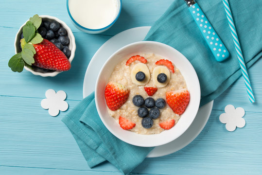 Funny oat porridge with owl face made of berries, food for kids idea, top view