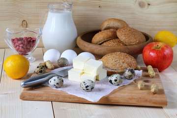 Natural products for breakfast and cooking. Dairy products, eggs and rye bread are on a wooden background.
