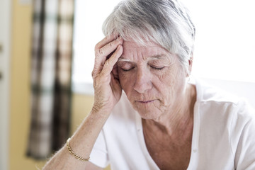 Mature woman at home touching her head with her hands while having a headache pain