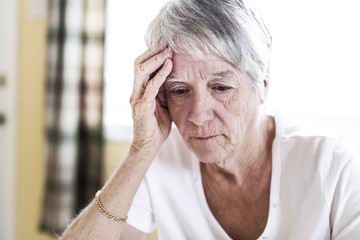Mature woman at home touching her head with her hands while having a headache pain