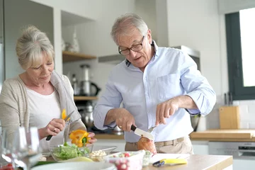 Foto auf Acrylglas Senior couple cooking together in home kitchen © goodluz