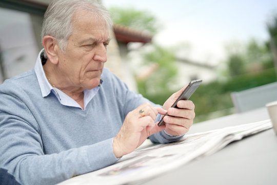 Senior Man Reading Newspaper Outside In Yard