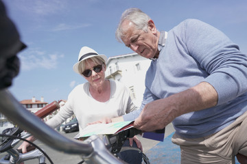 Fototapeta na wymiar Senior couple having fun riding bike in tourist area